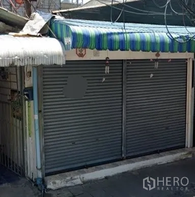 พื้นที่ขายปลีก ให้เช่าในWatthana, Bangkok - ด้านหน้าร้านติดถนน มีประตูม้วนโลหะคู่และกันสาดลายทางในซอยแคบ