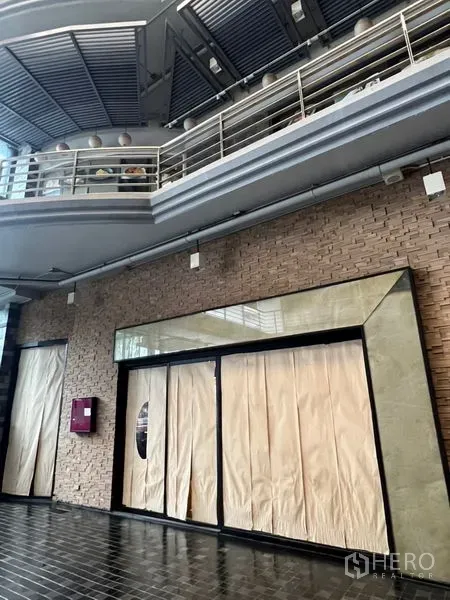 零售空间 出租 - 现代店面外立面，大片玻璃与砖墙，位于有顶连廊内。