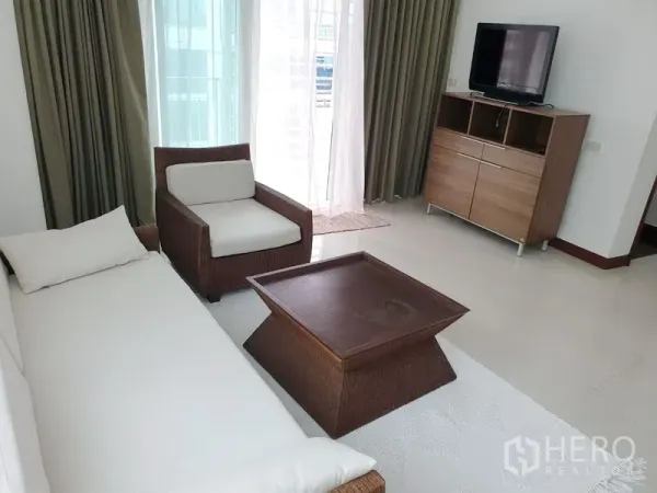 คอนโด ให้เช่าหรือขายในPathum Wan, Bangkok - มุมนั่งเล่นพร้อมโซฟา เก้าอี้อาร์มแชร์ ตู้ทีวี และประตูกระจกบานเลื่อนออกไประเบียง