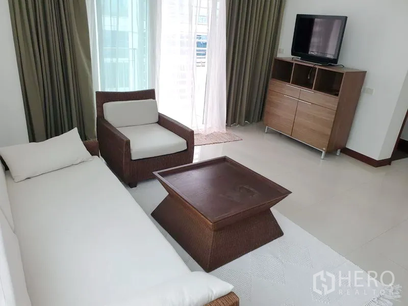 คอนโด ให้เช่าหรือขายในPathum Wan, Bangkok - มุมนั่งเล่นพร้อมโซฟา เก้าอี้อาร์มแชร์ ตู้ทีวี และประตูกระจกบานเลื่อนออกไประเบียง