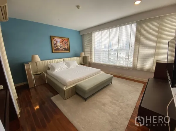 Condominium for rent in Watthana, Bangkok - Master bedroom with king bed, blue accent wall and wide city-view windows.