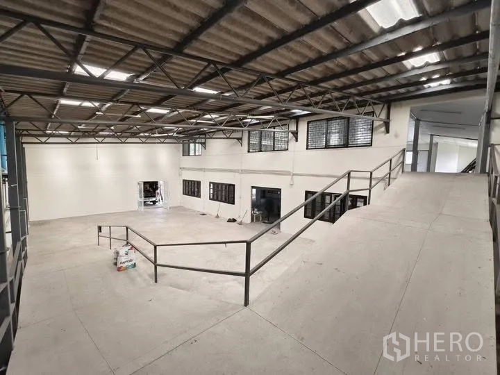 Warehouse for rent in Prawet, Bangkok - Interior loading ramp leading to a raised floor under a truss roof with skylights.