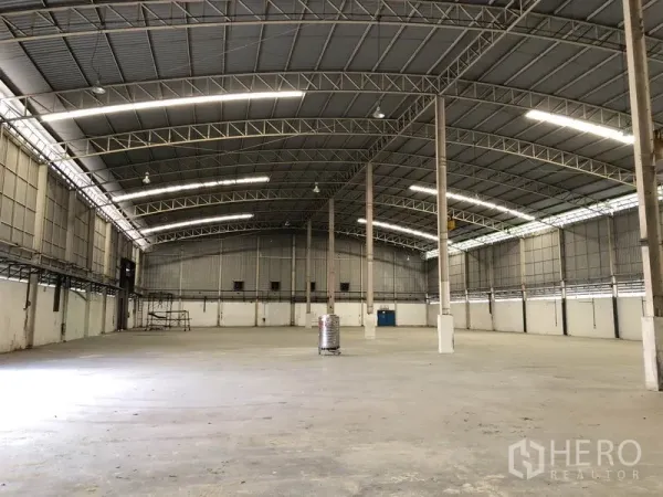 工厂 出租在Phra Nakhon Si Ayutthaya - 空旷仓库内部，拱形钢结构屋顶、混凝土地面与采光板。