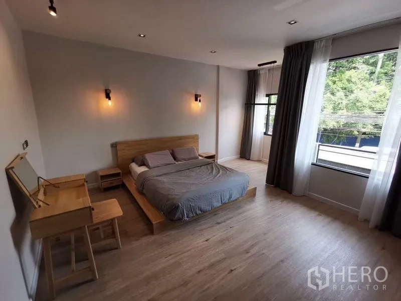 Townhouse for rent in Din Daeng, Bangkok - Spacious master bedroom with large corner windows, platform bed and wood floors.