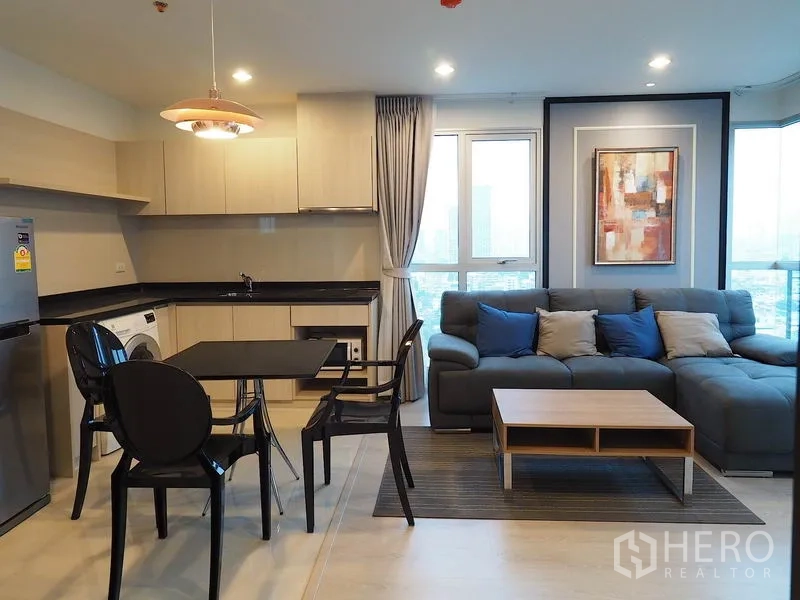 Condominium for rent in Sathon, Bangkok - Bright living space with corner sofa, coffee table and large windows overlooking the city.