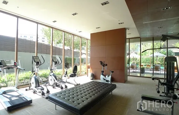 Condominium for rent or sale in Khlong Toei, Bangkok - Glass-walled fitness center with cardio machines overlooking the garden and pool.