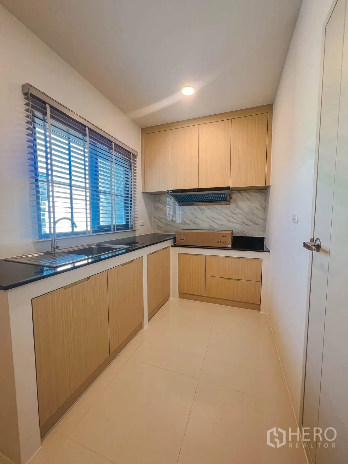 独栋房屋 for rent in Bang Phli, Samut Prakan - 紧凑厨房，木质橱柜、黑色台面、窗边水槽与吸油烟机。