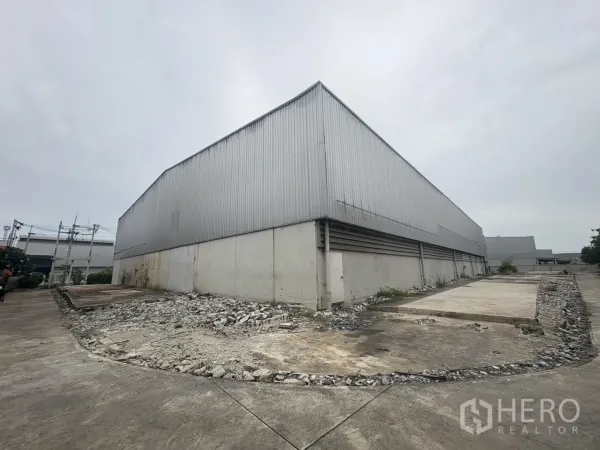 Factory for rent or sale in Samut Prakan - Rear corner of the warehouse with a raised concrete platform and service yard.