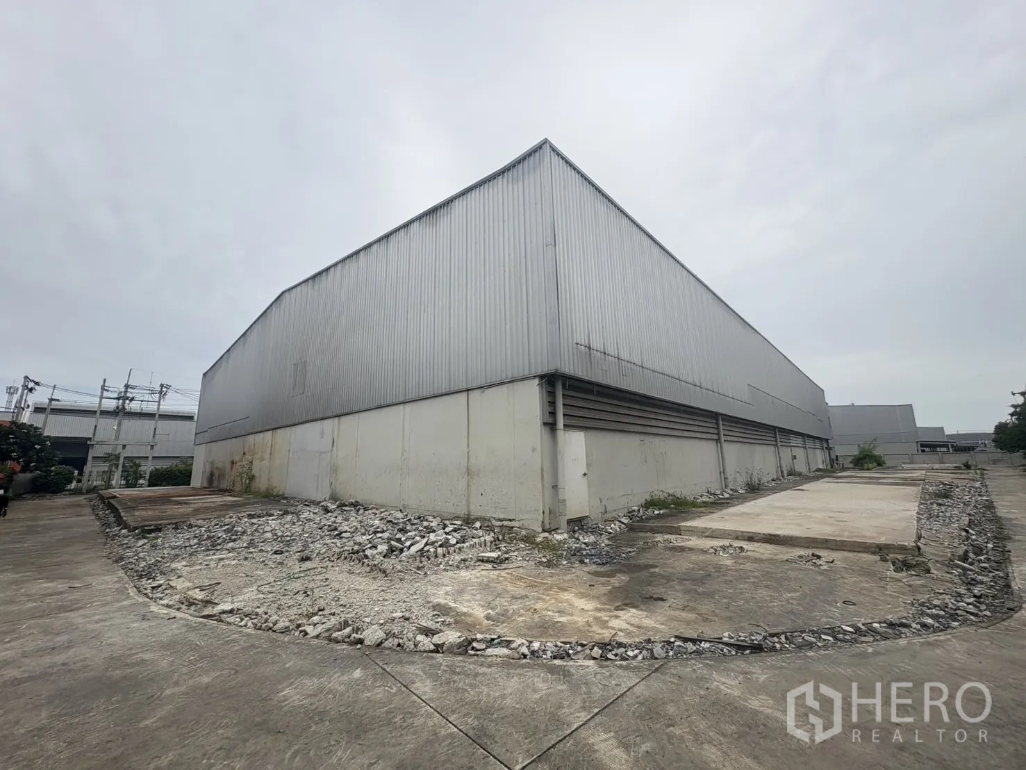 Factory for rent or sale in Samut Prakan - Rear corner of the warehouse with a raised concrete platform and service yard.