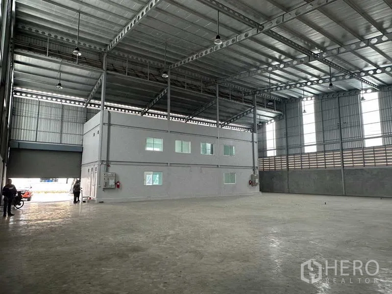 คลังสินค้า ให้เช่าในSamut Prakan - ภาพมุมเอียงของพื้นโกดัง ประตูม้วนขนาดใหญ่ เพดานสูงและช่องแสง.