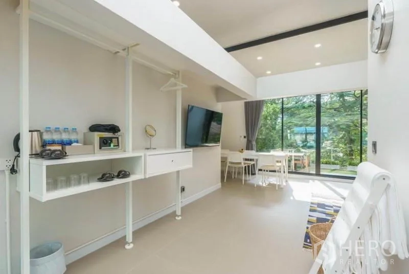 ทาวน์เฮาส์ ให้เช่าในKhlong Toei, Bangkok - พื้นที่เปิดโล่งพร้อมชั้นเก็บของ ทีวีติดผนัง และประตูกระจกสไลด์สู่สวน