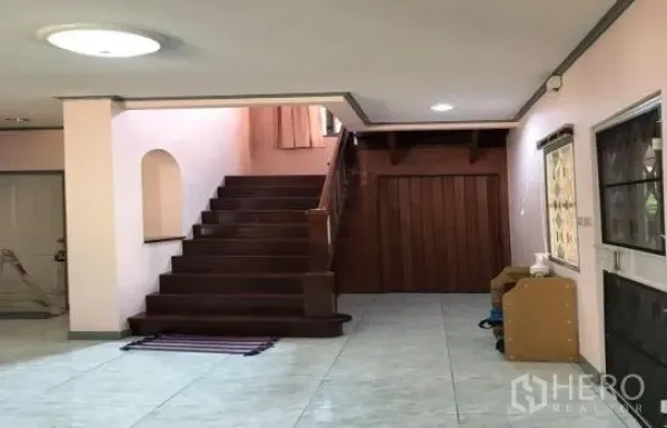 Detached House for rent in Khlong Sam Wa, Bangkok - Open foyer with tiled flooring and a wooden staircase leading upstairs, with storage under the stairs.