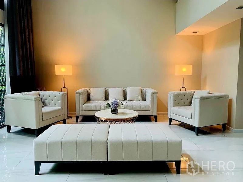 ทาวน์เฮาส์ ให้เช่าในWatthana, Bangkok - ห้องนั่งเล่นโทนเบจ เซ็ตโซฟา ออตโตมัน และโคมไฟ เพดานสูง