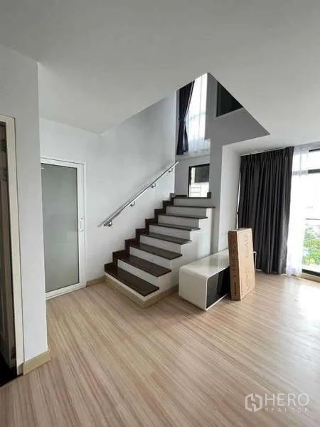 公寓 出租在Sathon, Bangkok - 沙吞公寓内，木地板与现代楼梯的明亮起居区