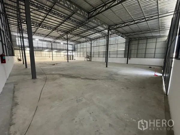 Warehouse for rent in Bang Kapi, Bangkok - Spacious warehouse interior with high steel truss roof, clear-span concrete floor, and natural light panels.
