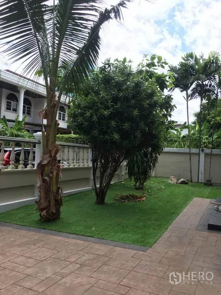Detached House for rent in Khlong Toei, Bangkok - Private front yard with manicured lawn, palm trees and a paved walkway.