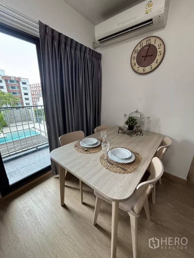 Condominium for rent in Phra Khanong, Bangkok - Four-seat dining table next to sliding door and curtains overlooking the condominium pool.