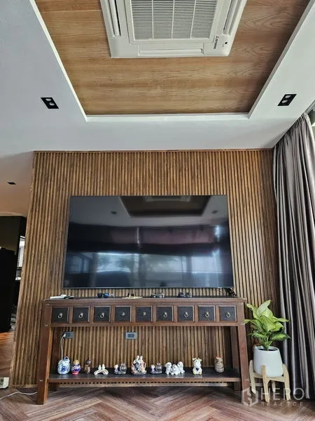 Detached House for sale in Thawi Watthana, Bangkok - Feature wall with vertical wood slats, large TV and a recessed ceiling panel.