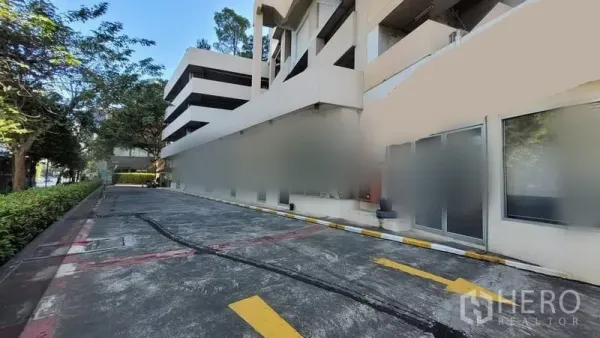 零售空间 出租在Khlong Toei, Bangkok - 低层商业建筑外观，车行通道与绿化带，底层玻璃店面