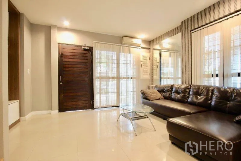 ทาวน์เฮาส์ ขายในSuan Luang, Bangkok - ห้องนั่งเล่น ประตูไม้บานใหญ่ หน้าต่างกระจก และโซฟาเข้ามุม