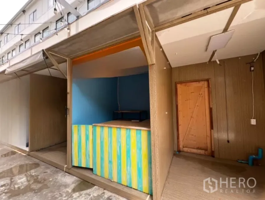 พื้นที่ขายปลีก ให้เช่าในKhlong Toei, Bangkok - คีออสหน้าร้านเปิดโล่ง เคาน์เตอร์ลายสีสัน ผนังไม้ และกันสาดแบบยกขึ้น ในโครงการลานกลางแจ้ง