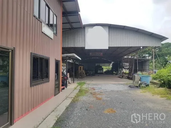 Warehouse for rent in Sai Noi, Nonthaburi - Front view of the warehouse and office block with a wide gravel driveway.