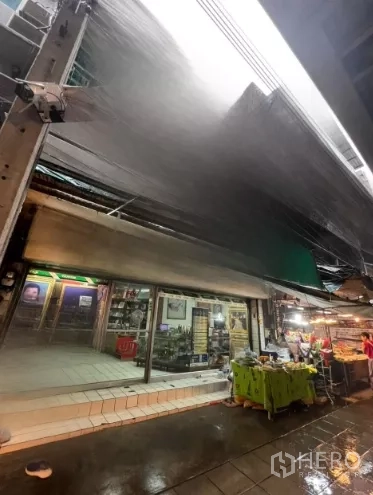 店屋 出租在Watthana, Bangkok - 带金属雨棚的商铺立面，临近湿滑的市场通道