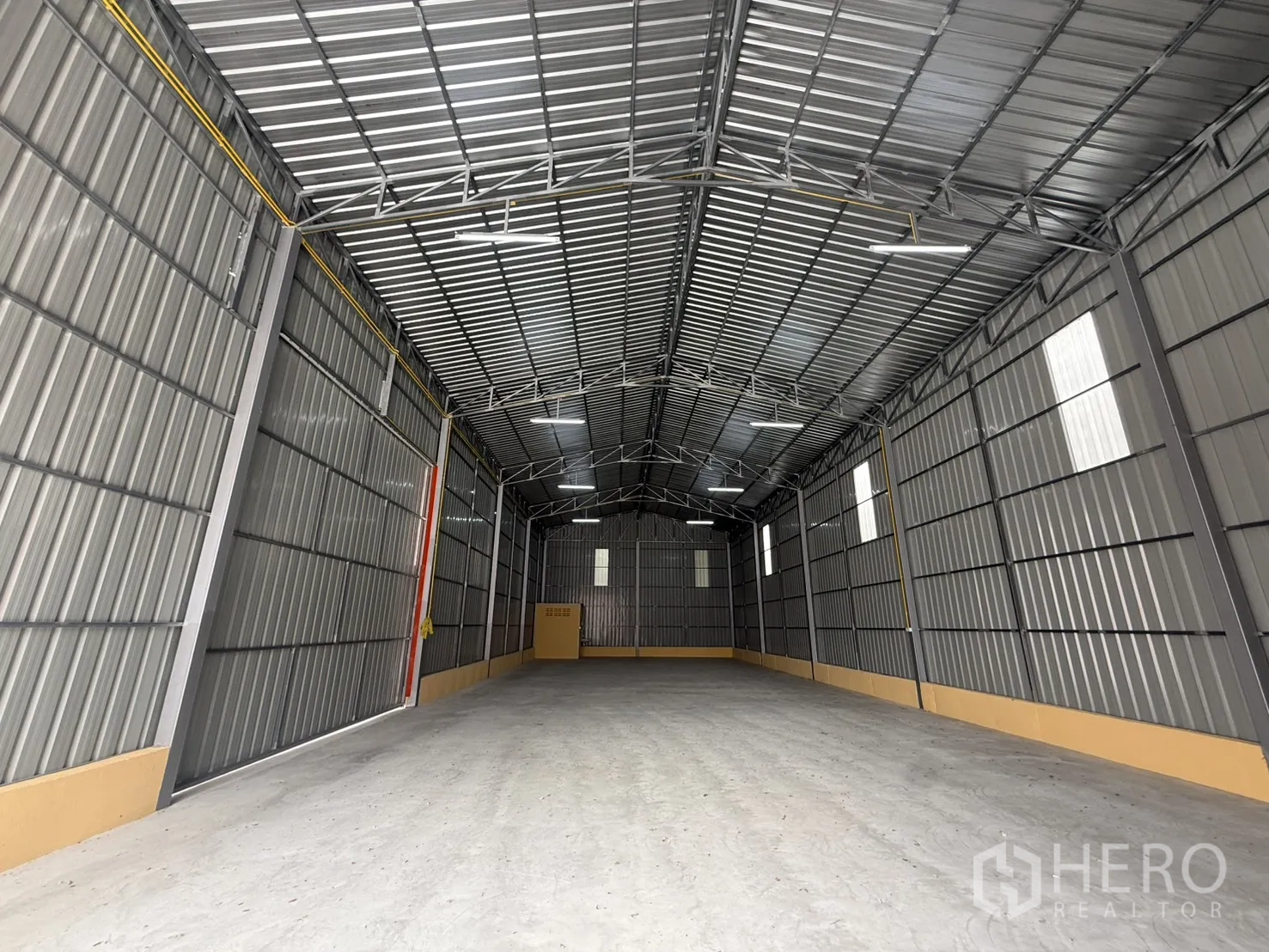 Warehouse for rent in Wang Thonglang, Bangkok - Interior of the warehouse showing a high steel roof, LED lighting, and smooth concrete floor.