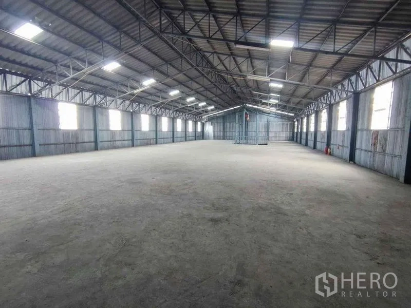 货栈 出租在Samut Sakhon - 高跨距仓库大厅，钢桁架屋顶与侧窗引入自然光。