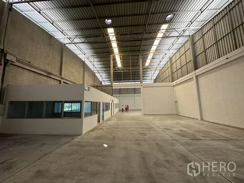 Factory for rent in Bang Phli, Samut Prakan - Long warehouse aisle with skylights and a white internal office structure.