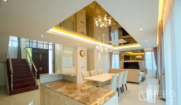 Detached House for rent in Bang Bon, Bangkok - Dining area and marble island beside the wooden staircase and double-height entry hall.
