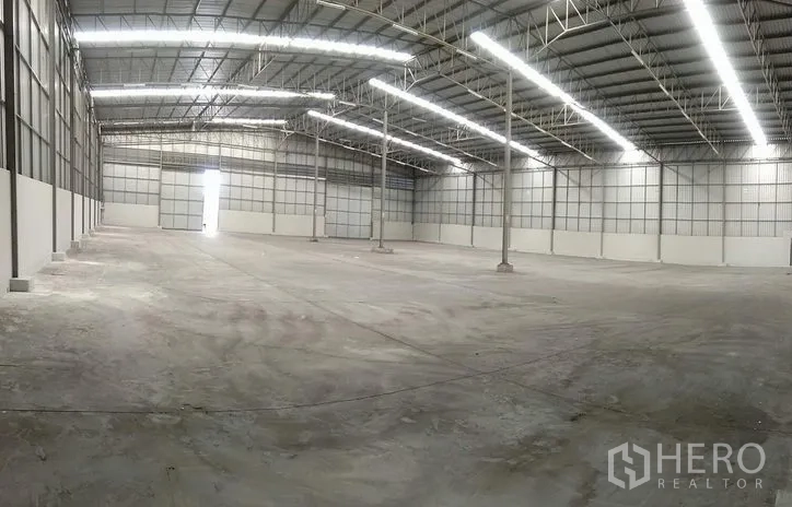 คลังสินค้า ให้เช่าในBang Phli, Samut Prakan - ภาพมุมกว้างภายในโกดัง เสากลางหลายต้น ช่องแสง และประตูม้วนอุตสาหกรรม
