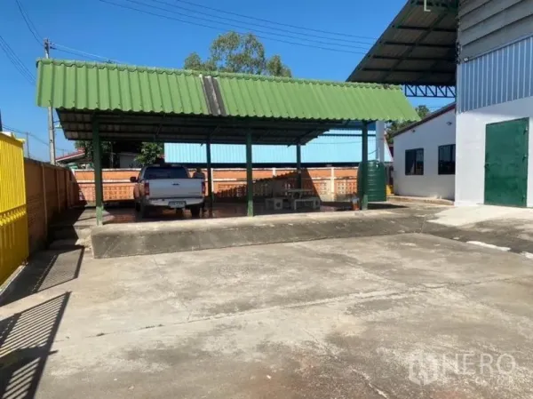 Warehouse for rent in Mueang Rayong, Rayong - Covered loading and parking bay with a green roof and concrete yard inside the compound.