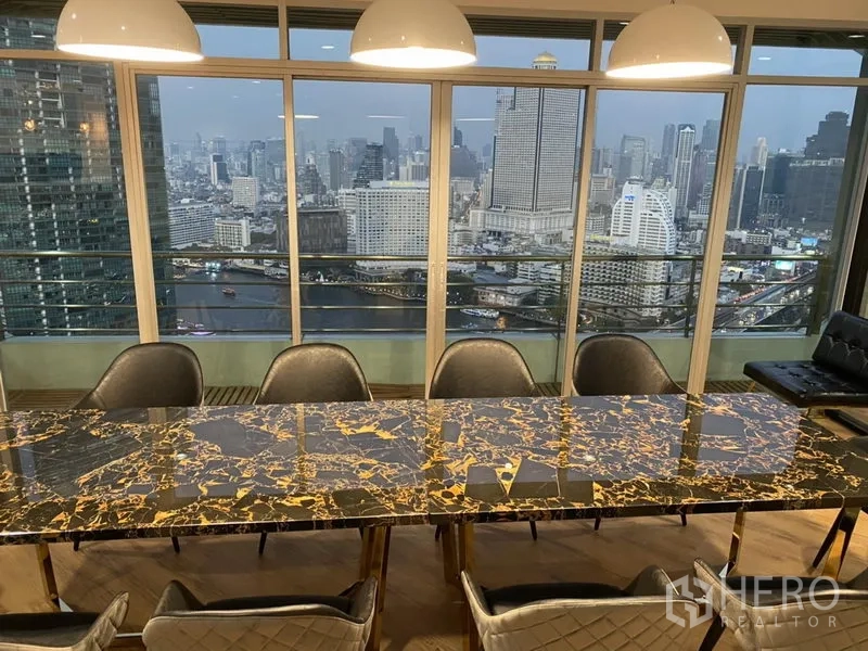 คอนโด ให้เช่าหรือขายในKhlong San, Bangkok - พื้นที่รับประทานอาหารโต๊ะหินอ่อน กระจกสูงจรดเพดานมองเห็นวิวแม่น้ำเจ้าพระยาและสกายไลน์ยามค่ำ
