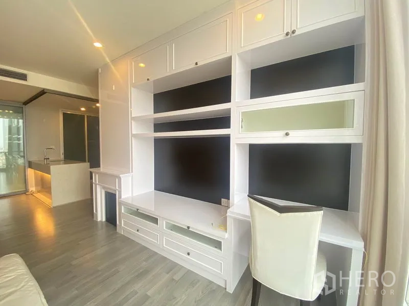 公寓 出租在Bang Rak, Bangkok - 客厅配大面积内置柜体，面向开放式厨房与推拉玻璃门。