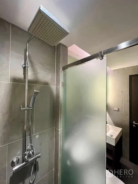 คอนโด ให้เช่าหรือขาย - ห้องน้ำโมเดิร์น ฝักบัวเรนชาวเวอร์ กระเบื้องสีเทา และประตูกระจกฝ้าแบบสไลด์