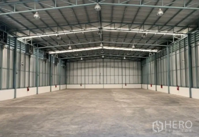 Warehouse for rent in Suan Luang, Bangkok - Spacious warehouse interior with high steel truss ceiling, concrete floor, and skylight panels.