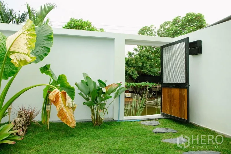 บ้าน ขายในPhra Pradaeng, Samut Prakan - สวนส่วนตัวปลูกไม้ใบทรอปิคัล พร้อมประตูเปิดออกสู่ทัศนียภาพสระน้ำด้านนอก