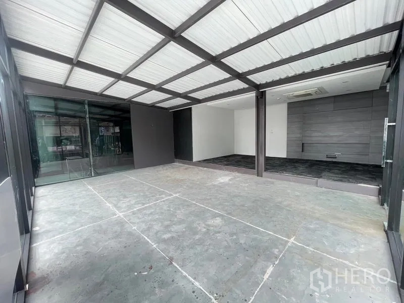 办公空间 出租在Bang Na, Bangkok - 带顶棚的入口，通向配有滑动玻璃门与深色地砖的现代办公室