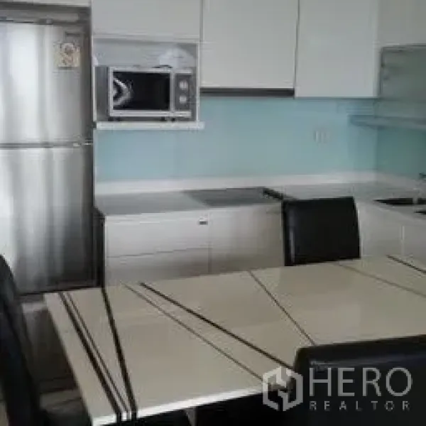 Condominium for rent in Sathon, Bangkok - Modern white kitchen with stainless refrigerator, built-in microwave and a dining table in a Bangkok condo.