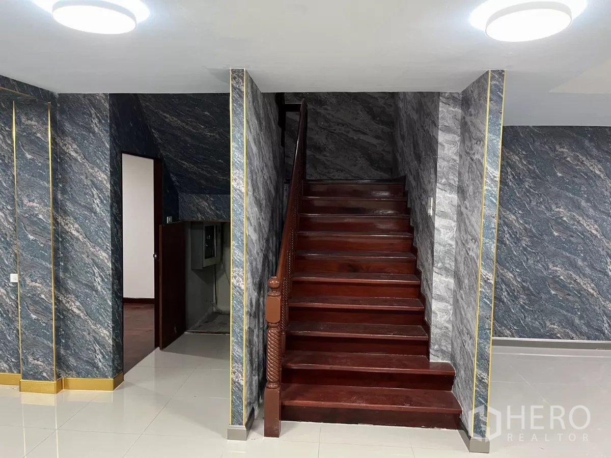 บ้าน ให้เช่าในWatthana, Bangkok - อีกมุมของโถงกลาง เน้นบันไดไม้และพื้นกระเบื้องเงา.