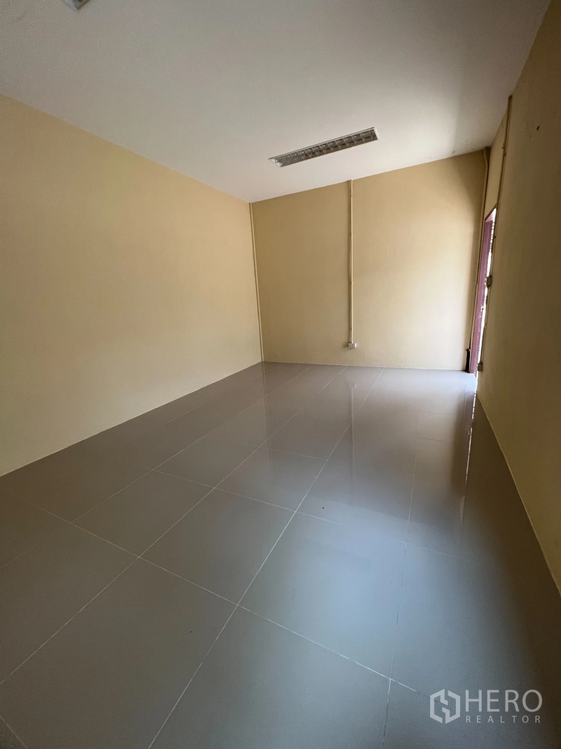 Warehouse for sale in Bang Len, Nakhon Pathom - Empty room with glossy tiles and warm-toned walls suitable for office or staff use.