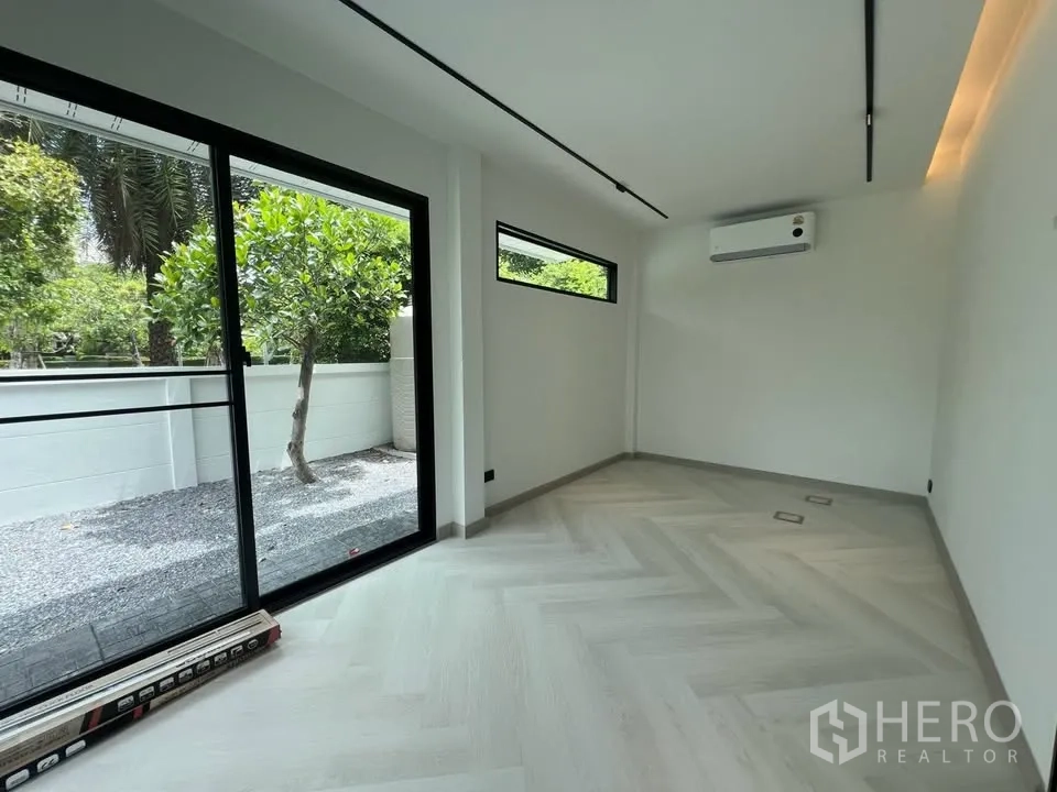 Townhouse for rent in Prawet, Bangkok - Bright room with sliding doors opening to gravel yard and air conditioner.