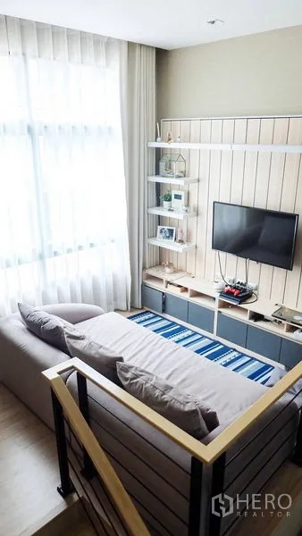 ทาวน์เฮาส์ ให้เช่าหรือขายในSuan Luang, Bangkok - มุมนั่งเล่นทีวี โซฟาและชั้นวางสื่อ ติดบันได พร้อมพรมลายทาง