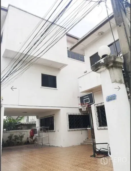 Detached House for sale in Khlong San, Bangkok - Three-storey white detached house with a tiled forecourt and basketball hoop in Khlong San, Bangkok.