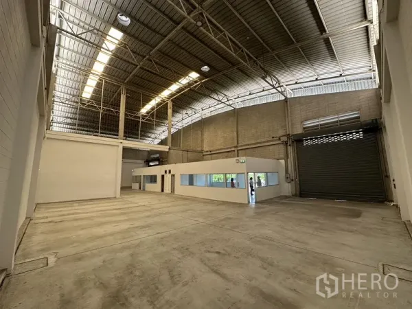 Factory for rent in Bang Phli, Samut Prakan - High-ceiling production hall with skylights, concrete floors and an internal office module.