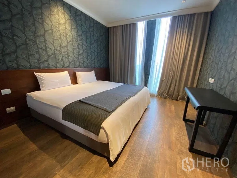 คอนโด ให้เช่าในPathum Wan, Bangkok - ห้องนอนมาสเตอร์พร้อมม้านั่งริมหน้าต่าง ชั้นวางบิลท์อิน และวอลเปเปอร์ลายดอก