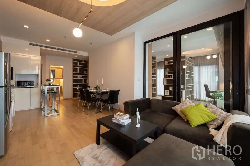 คอนโด ขายในWatthana, Bangkok - พื้นที่นั่งเล่นกว้างพร้อมห้องทำงานกั้นกระจก โซฟาตัวแอล และมุมทานอาหารบนพื้นไม้