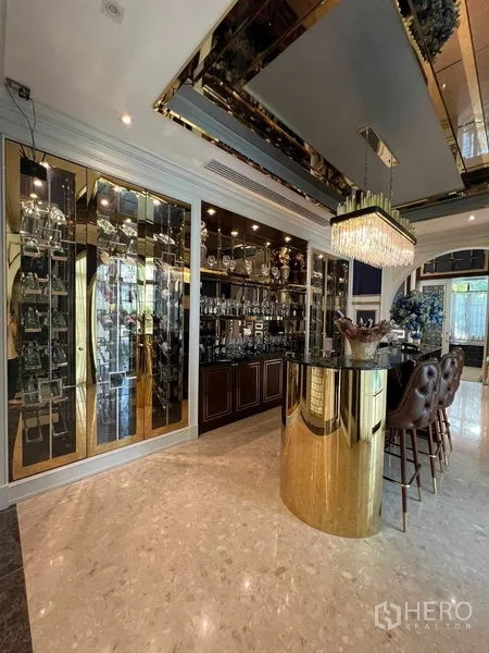 Detached House for rent or sale in Thawi Watthana, Bangkok - Luxurious home bar with a gold island, glass display cabinets and leather stools.