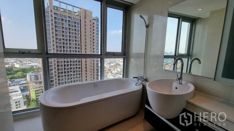 คอนโด ขายในWatthana, Bangkok - ห้องน้ำพร้อมอ่างอาบน้ำ วิวเมืองกว้าง และอ่างล้างหน้าใกล้หน้าต่างสูง